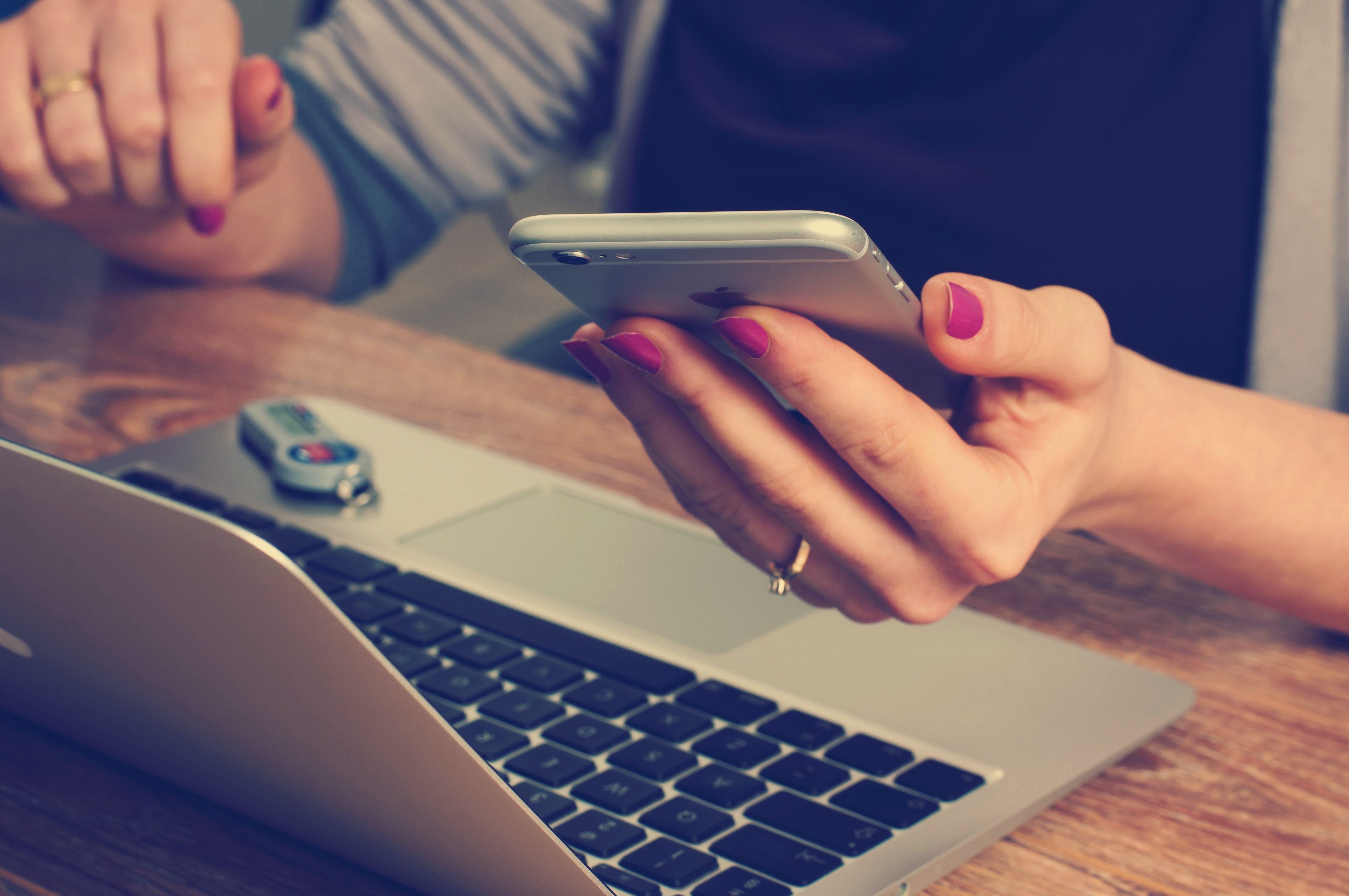 Person holding phone while on laptop